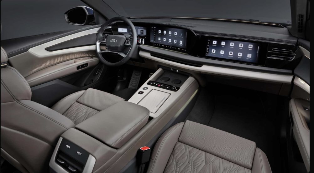 2027 Audi Q9 interior showing triple-screen setup under curved glass, icon-grid infotainment display, beige leather seats